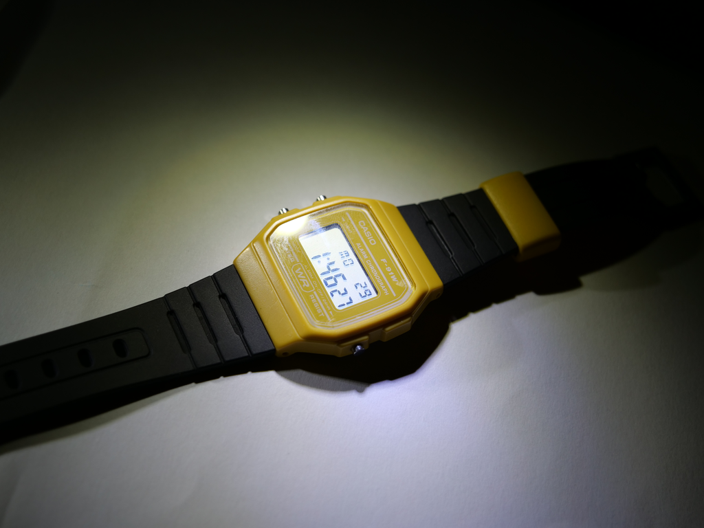 a shot of a yellow and black assembled sensor watch, lying horizontally on a surface