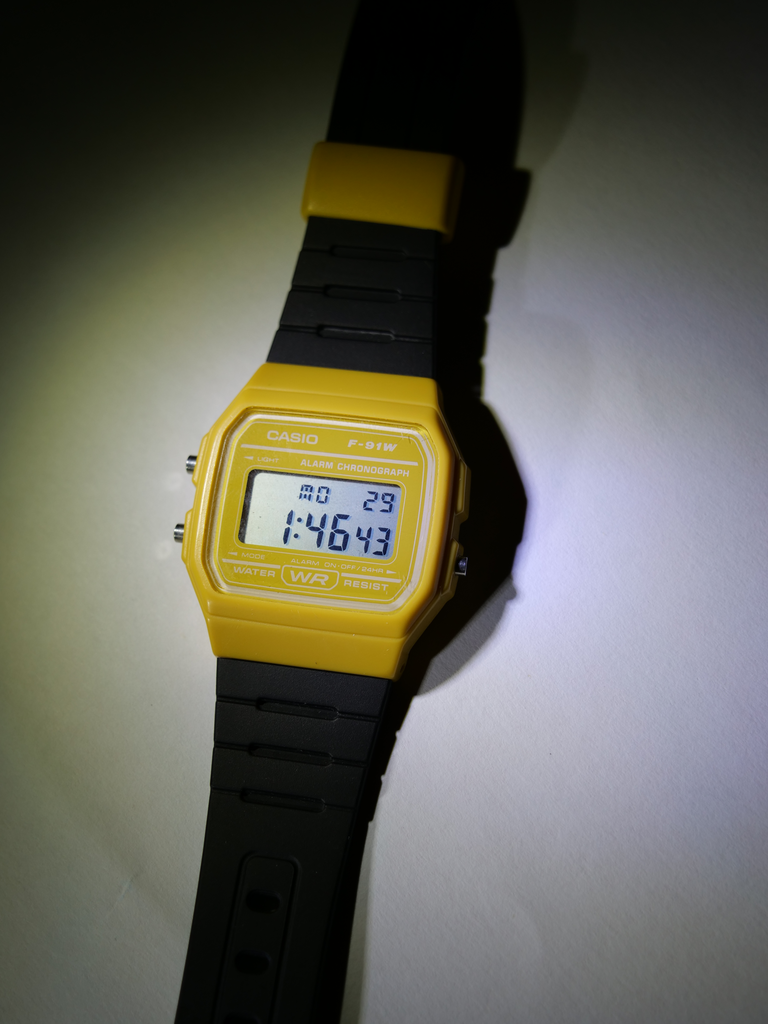 a shot of a yellow and black assembled sensor watch, lying vertically on a surface